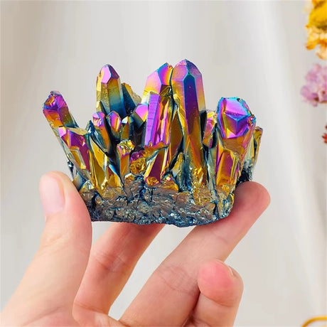 Multicolored crystal cluster held in a hand against a neutral background