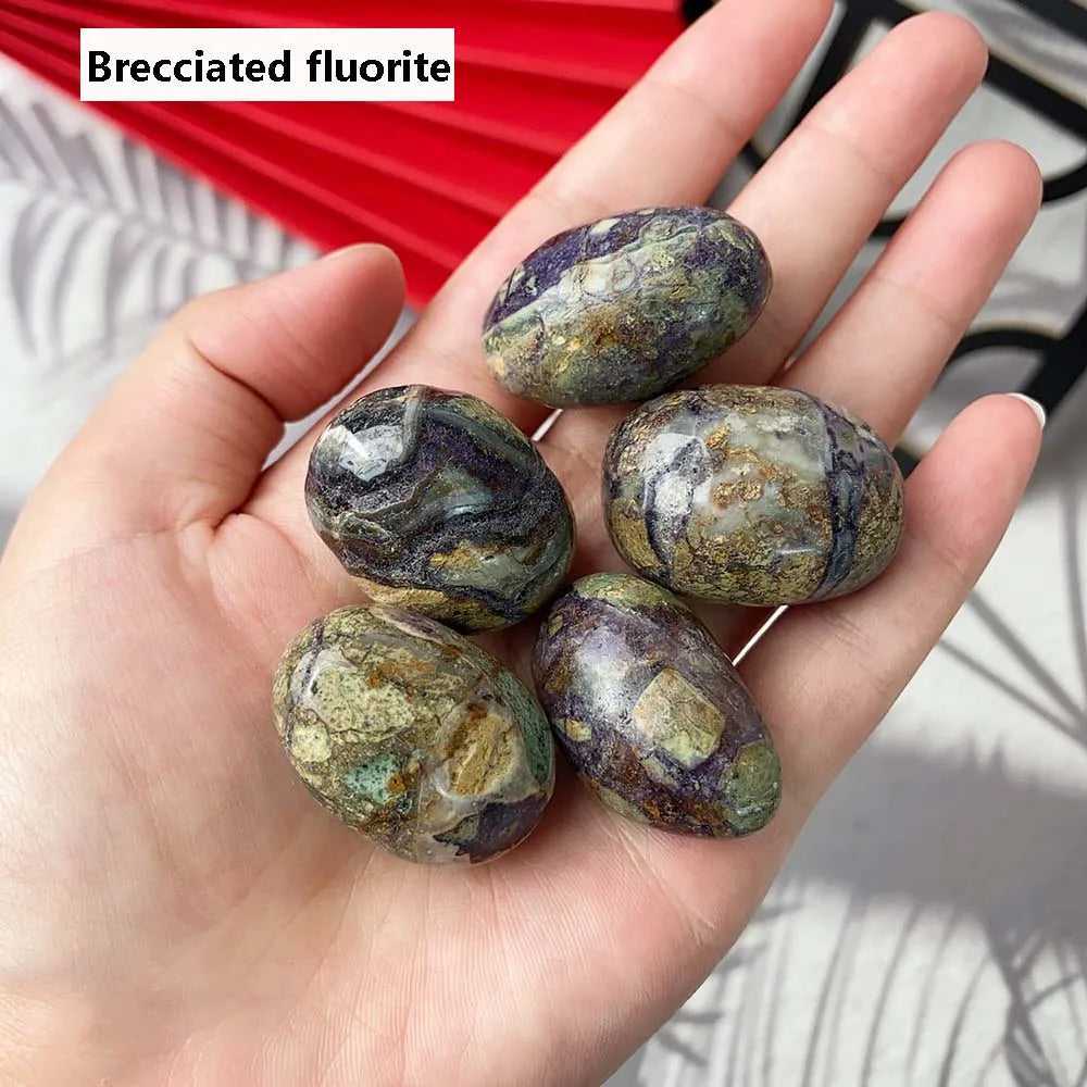 Hand holding brecciated fluorite crystals with a red and white striped background