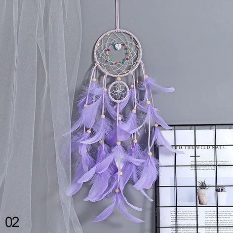 Purple dreamcatcher with feathers hanging against a gray curtain.