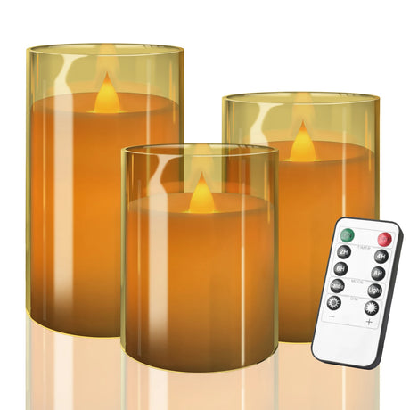 Set of three cylindrical orange candles with a remote control on a white background