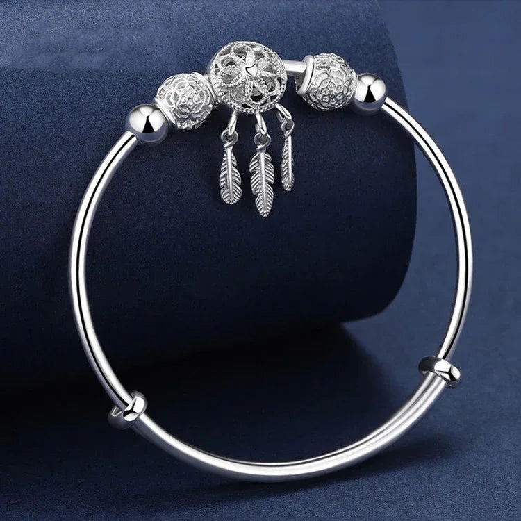 Silver bracelet with decorative beads and feathers on a dark blue background