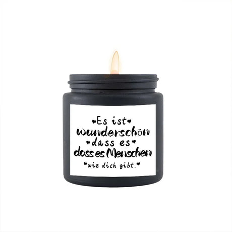 Black candle with a white label featuring German text on a white background