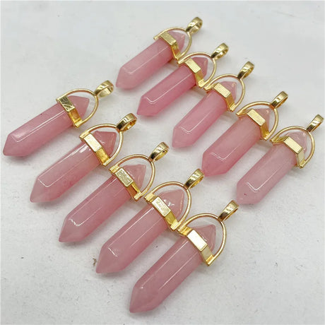 Pink crystal pendants with gold accents on a light gray background