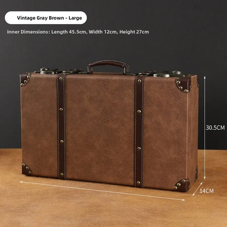 Brown vintage-style suitcase with measurements on a wooden surface and dark background