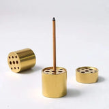 Brass incense burner with a single incense stick on a white background