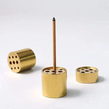 Brass incense burner with a single incense stick on a white background