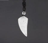 Crystal arrowhead pendant on a black cord against a dark background