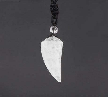 Crystal arrowhead pendant on a black cord against a dark background