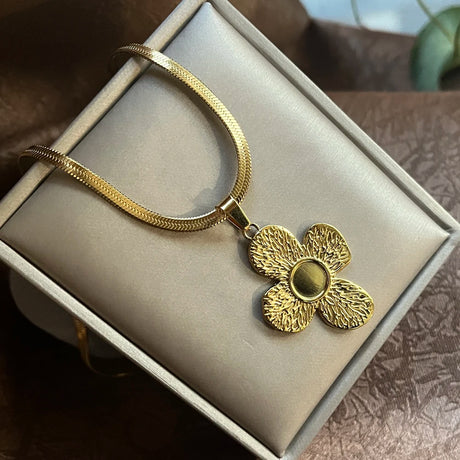 Gold necklace with a floral pendant on a beige box