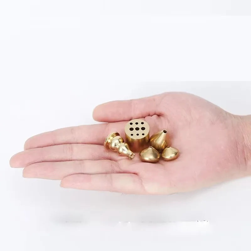 Hand holding small brass or bronze objects on a white background