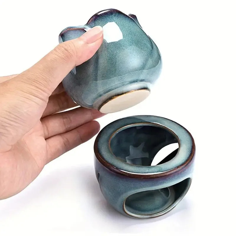 Hand holding a ceramic incense burner with a matching lid on a white background