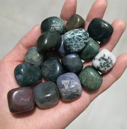Hand holding a collection of polished gemstones with various colors.