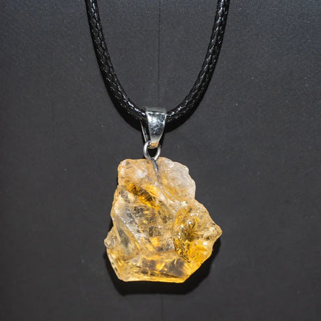 Mineral stone pendant on a black cord against a dark background
