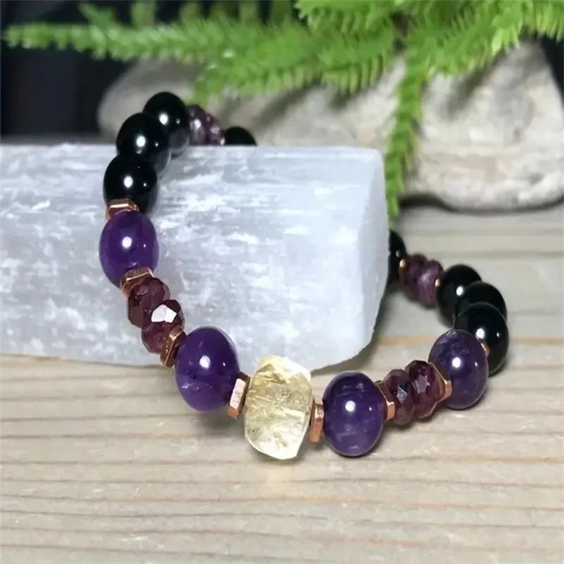 Multicolored beaded bracelet on a light wooden surface with greenery in the background