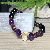 Multicolored beaded bracelet on a light wooden surface with greenery in the background