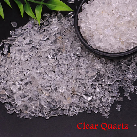 Clear quartz crystals with a bowl of quartz and green leaves on a black background
