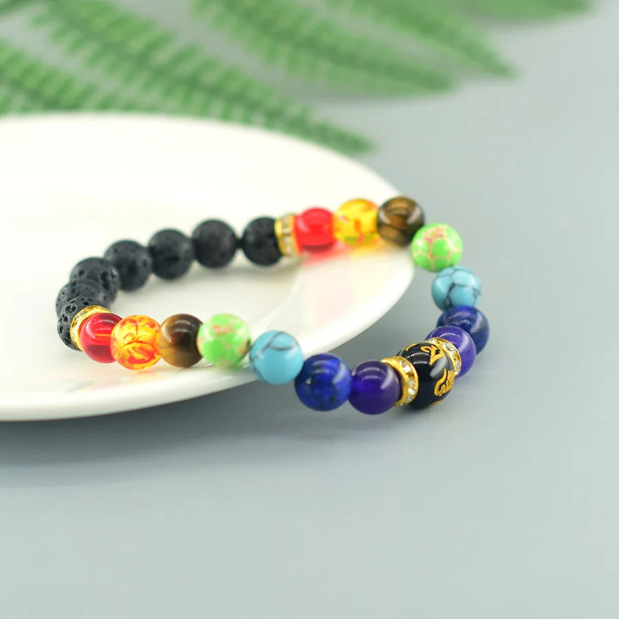 Multicolored beaded bracelet on a white plate with green leaves in the background