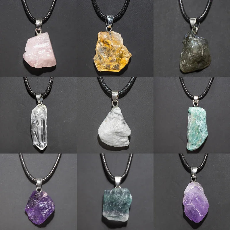Collection of various raw crystal pendants on black cords against a dark background