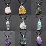 Collection of various raw crystal pendants on black cords against a dark background