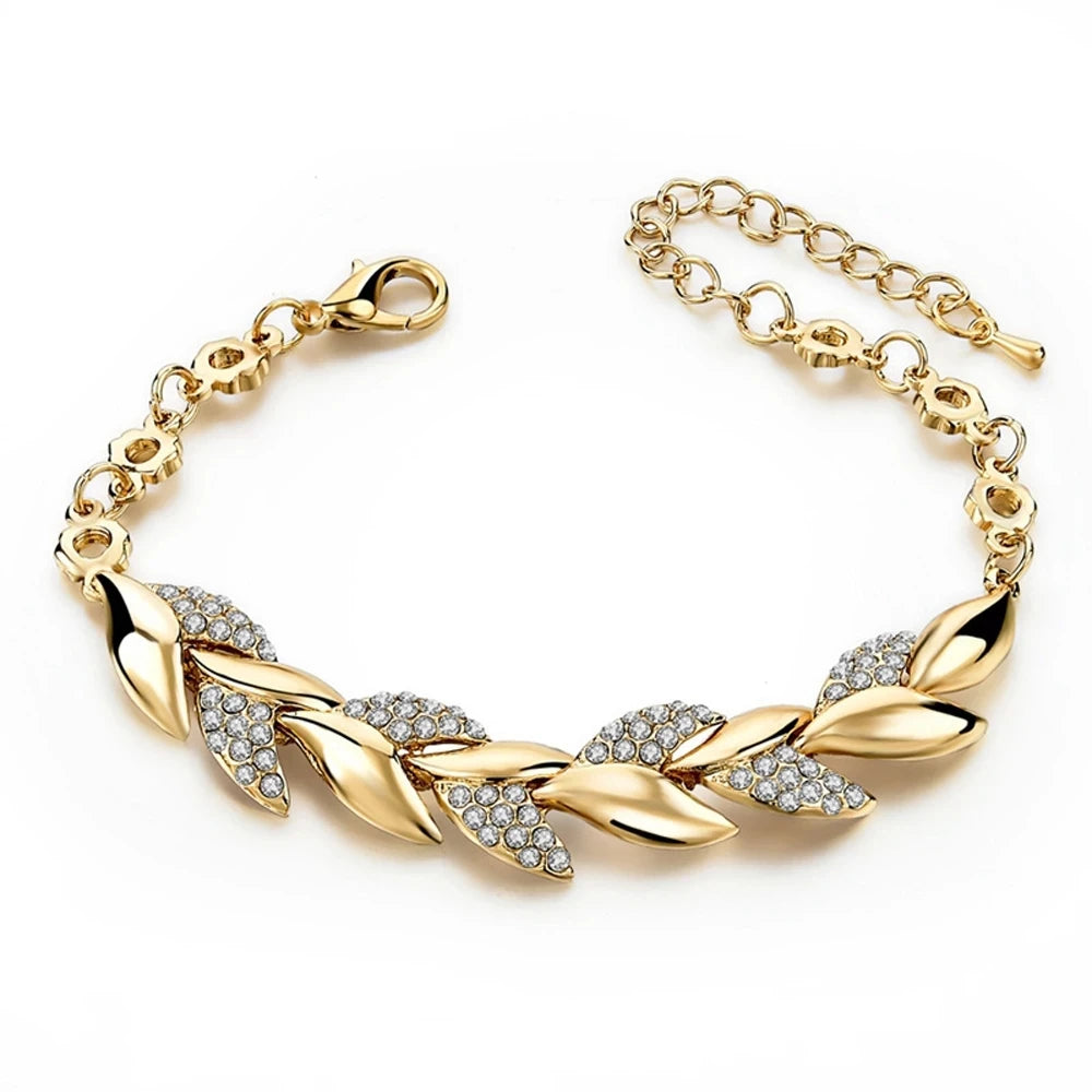 Gold bracelet with leaf designs and clear stones on a white background