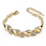 Gold bracelet with leaf designs and clear stones on a white background