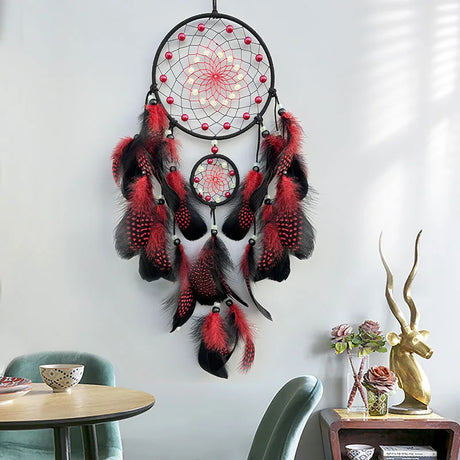 Decorative dreamcatcher with red and black feathers hanging on a wall.