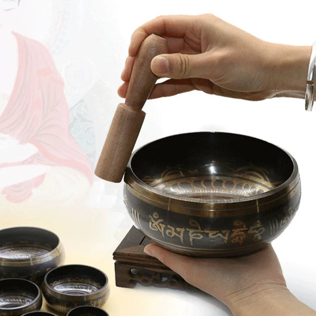 Hand holding a singing bowl with a wooden striker on a white background