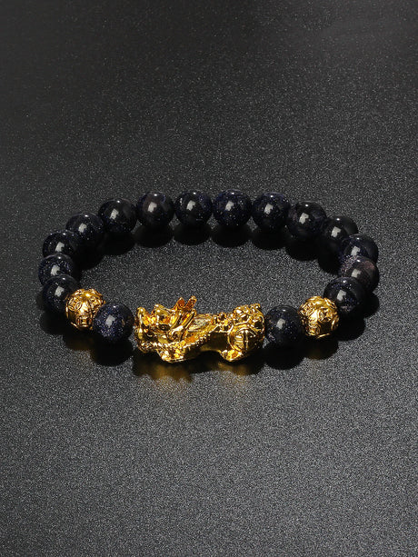 Black beaded bracelet with gold accents on a dark background