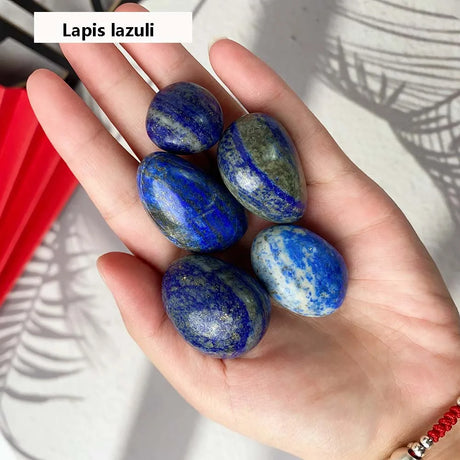 Hand holding lapis lazuli stones with a white background