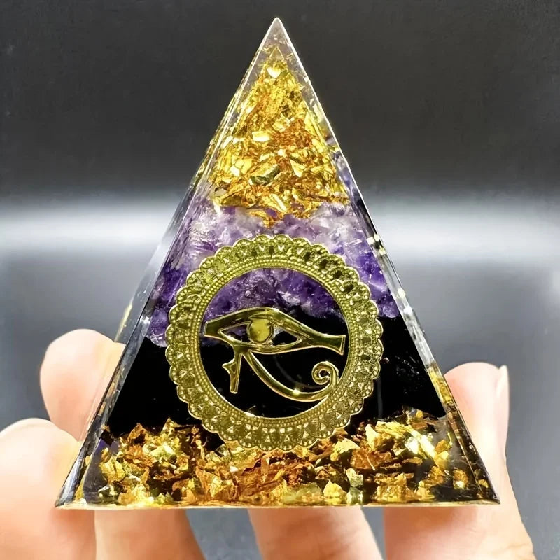 Triangular crystal with gold and purple elements held by a hand against a dark background