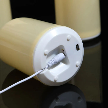 Close-up of a cylindrical device with a white cable plugged into it on a reflective surface.