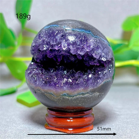 Amethyst crystal sphere with a wooden stand on a light background