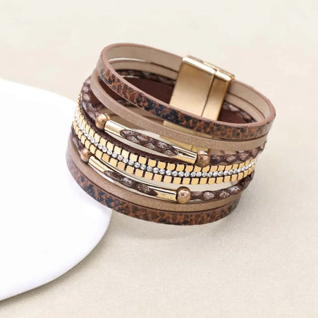 Stack of layered bracelets with gold and brown accents on a light background