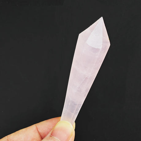 Hand holding a clear crystal point against a black background