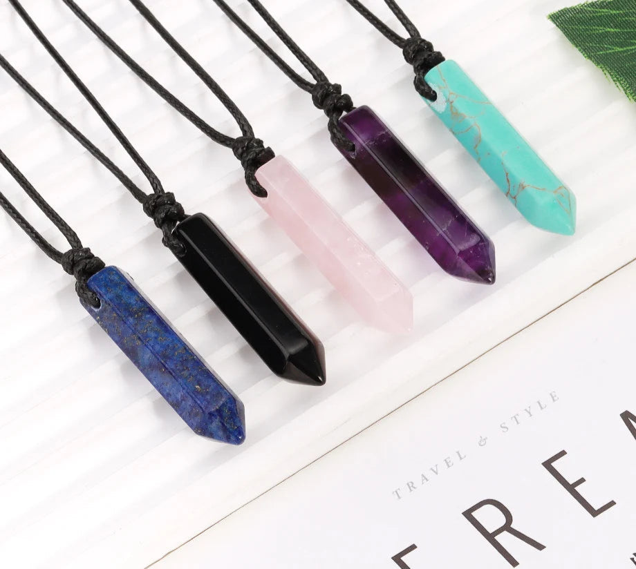 Set of crystal pendant necklaces on a white surface with visible brand logo.