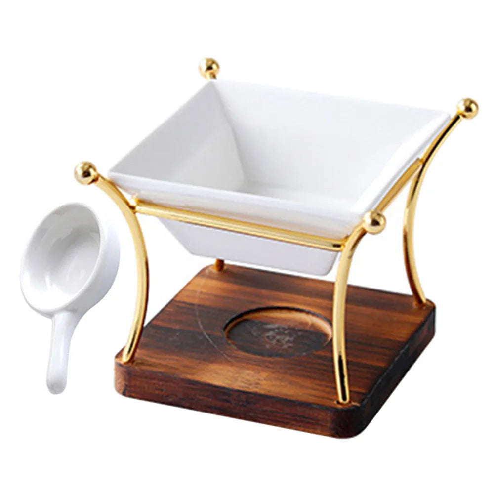 White square bowl on a gold stand with a wooden base, accompanied by a small white ladle.