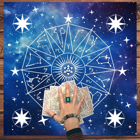 Hand holding tarot cards with star and zodiac symbol design on a blue celestial background