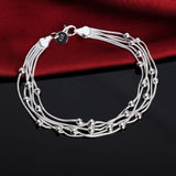 Silver bracelet with multiple strands on a dark surface with a red fabric background