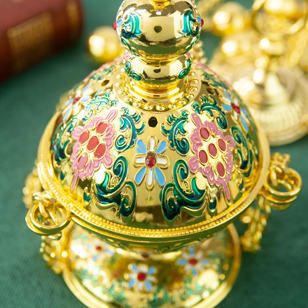 Decorative gold incense burner with floral designs on a green surface