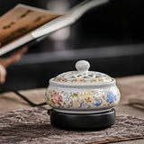 Decorative ceramic incense burner with floral patterns on a wooden surface.