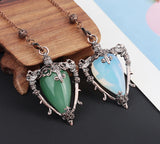 Two decorative pendants on a wooden stand with a colorful background
