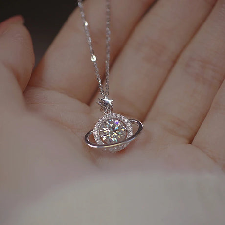 Silver necklace with a planet-shaped pendant held in a hand