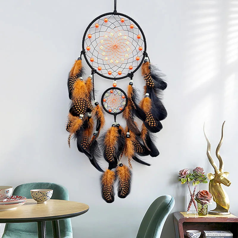Decorative dreamcatcher with feathers hanging on a wall in a room with a table and decorative items.