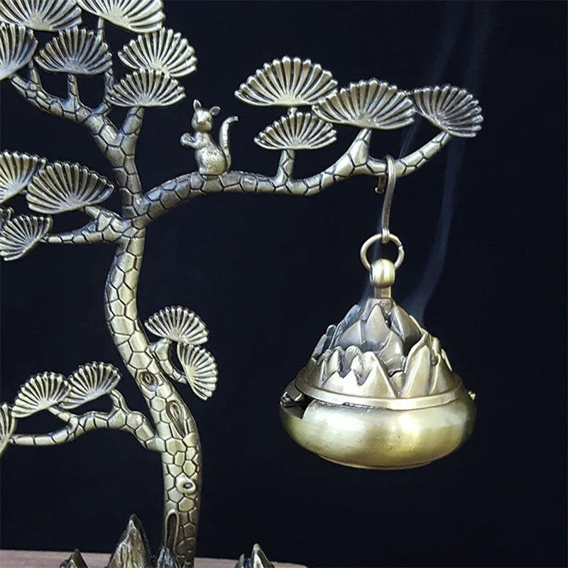 Decorative incense burner hanging from a tree branch with a dark background