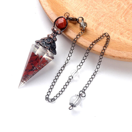 Pendulum with red stones and a chain on a white background