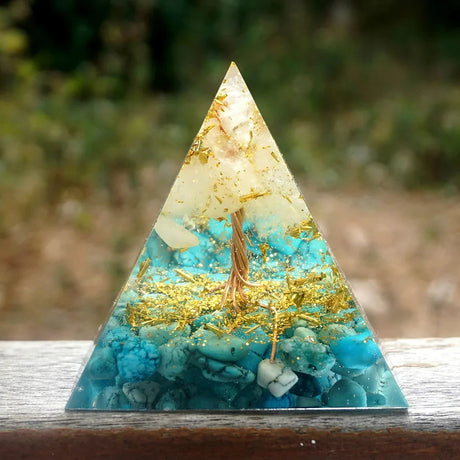 Triangular pyramid with turquoise and gold interior on a wooden surface
