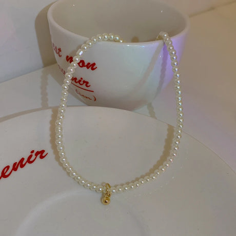 Pearl bracelet with a gold clasp on a white surface with red text