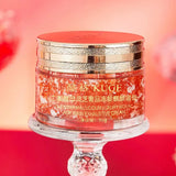Cosmetic jar with red and gold design on a stand against a blurred background