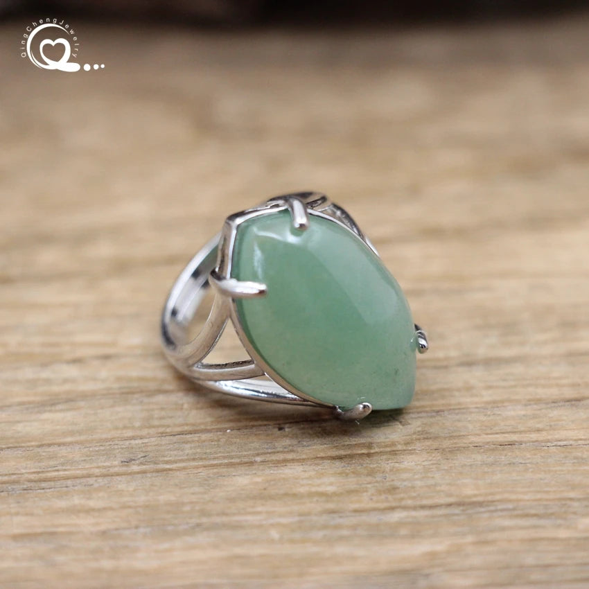 Silver ring with a green stone on a wooden surface