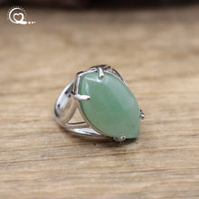 Silver ring with a green stone on a wooden surface